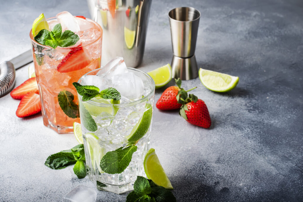 Mojito mocktail set with lime, mint, strawberry and ice in glass on gray background