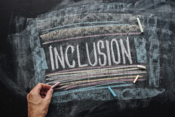 Teacher writing word Inclusion on school blackboard, inclusive education